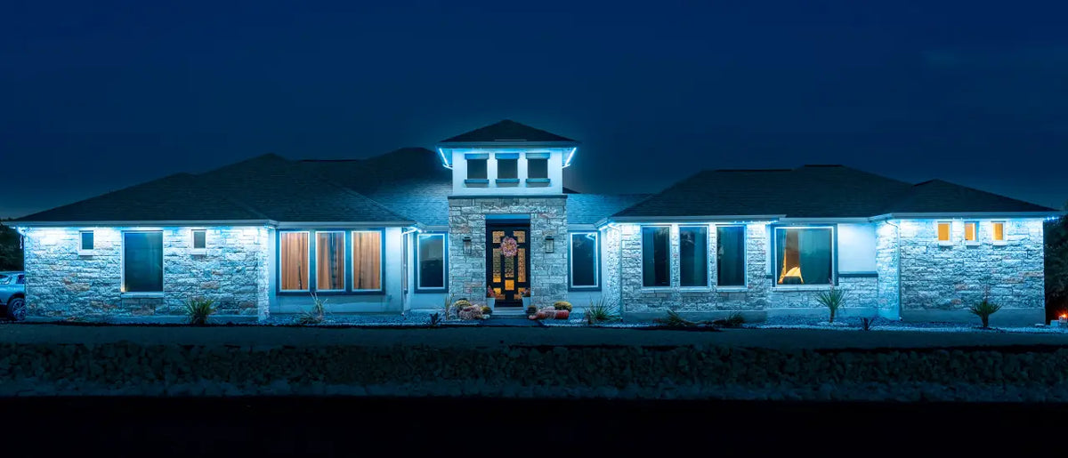 The same home after dark with permanent architectural lighting illuminated